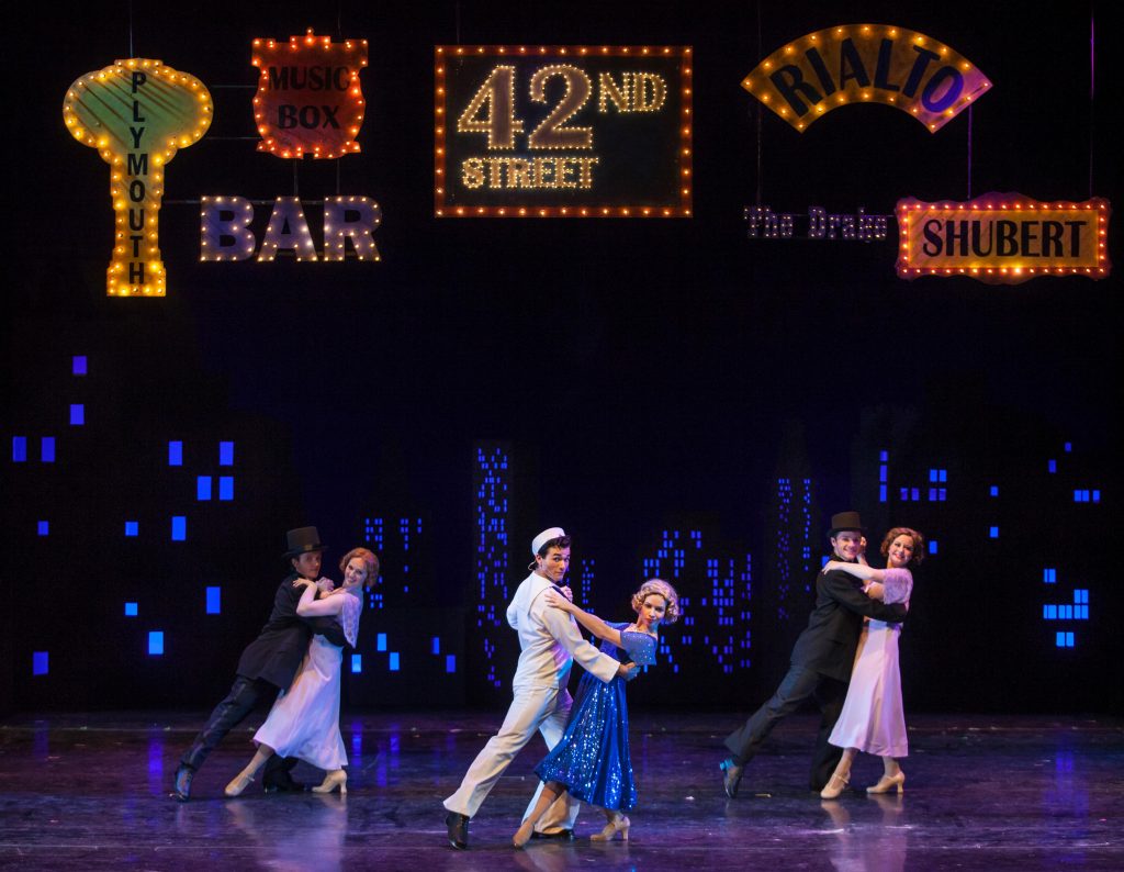 the set of 42nd Street, featuring neon signs and colorful lighting