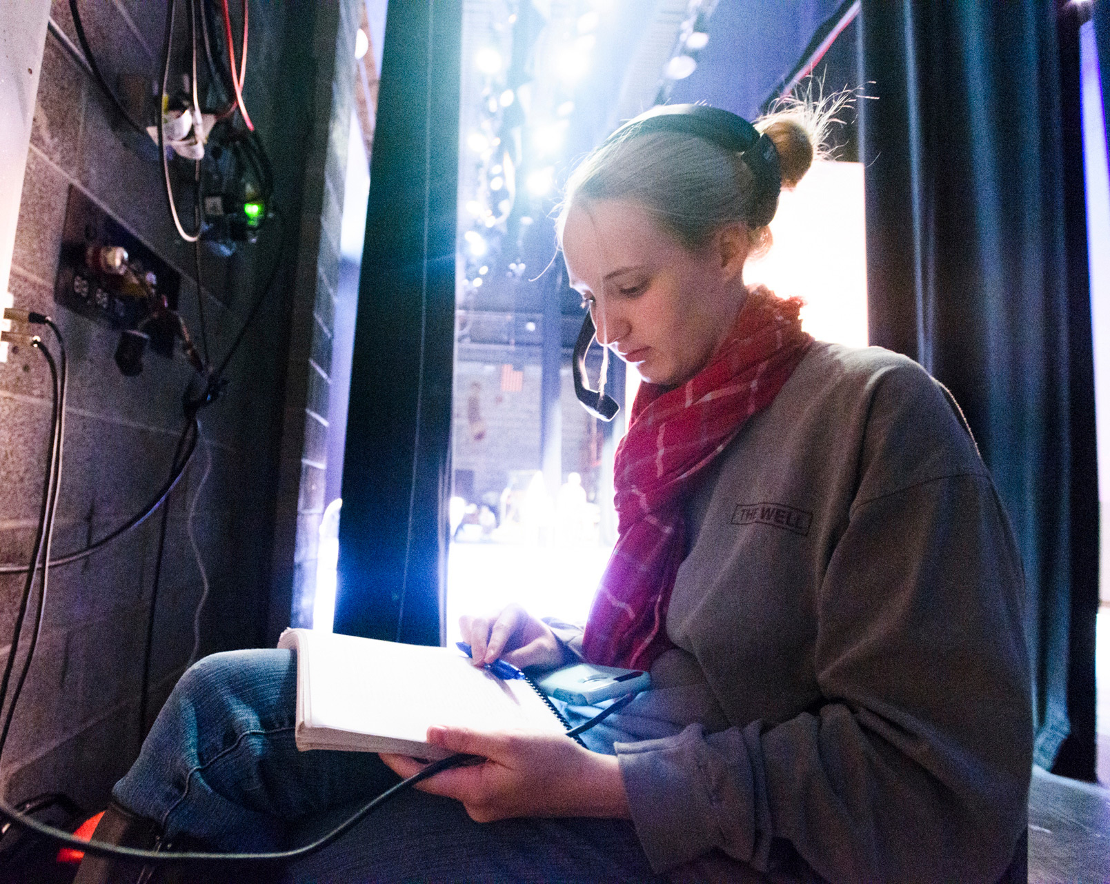 a student backstage wearing a headset and reading a script
